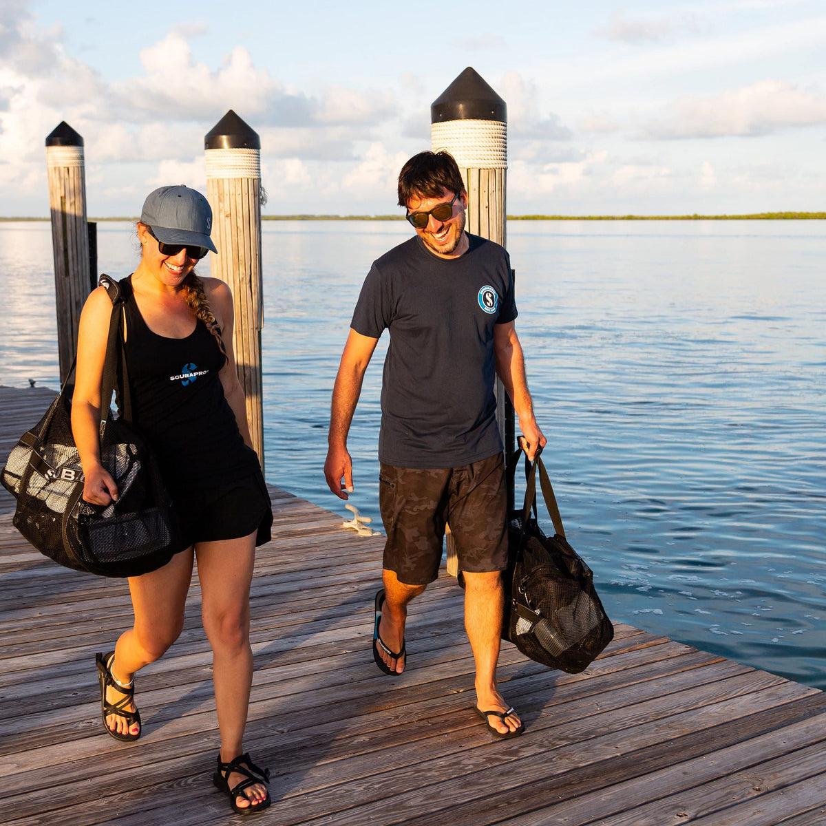 Couple walking off dock with bags, sunny day