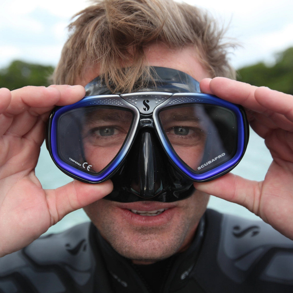 Scuba diver holding Scubapro mask, SP_24157002, looking at camera.