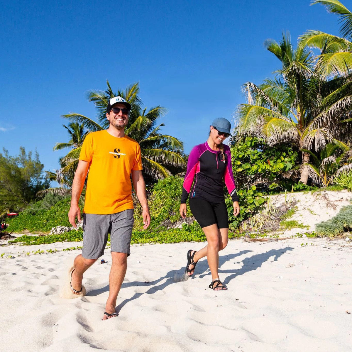 Men's orange crew t-shirt on beach with woman in swimwear