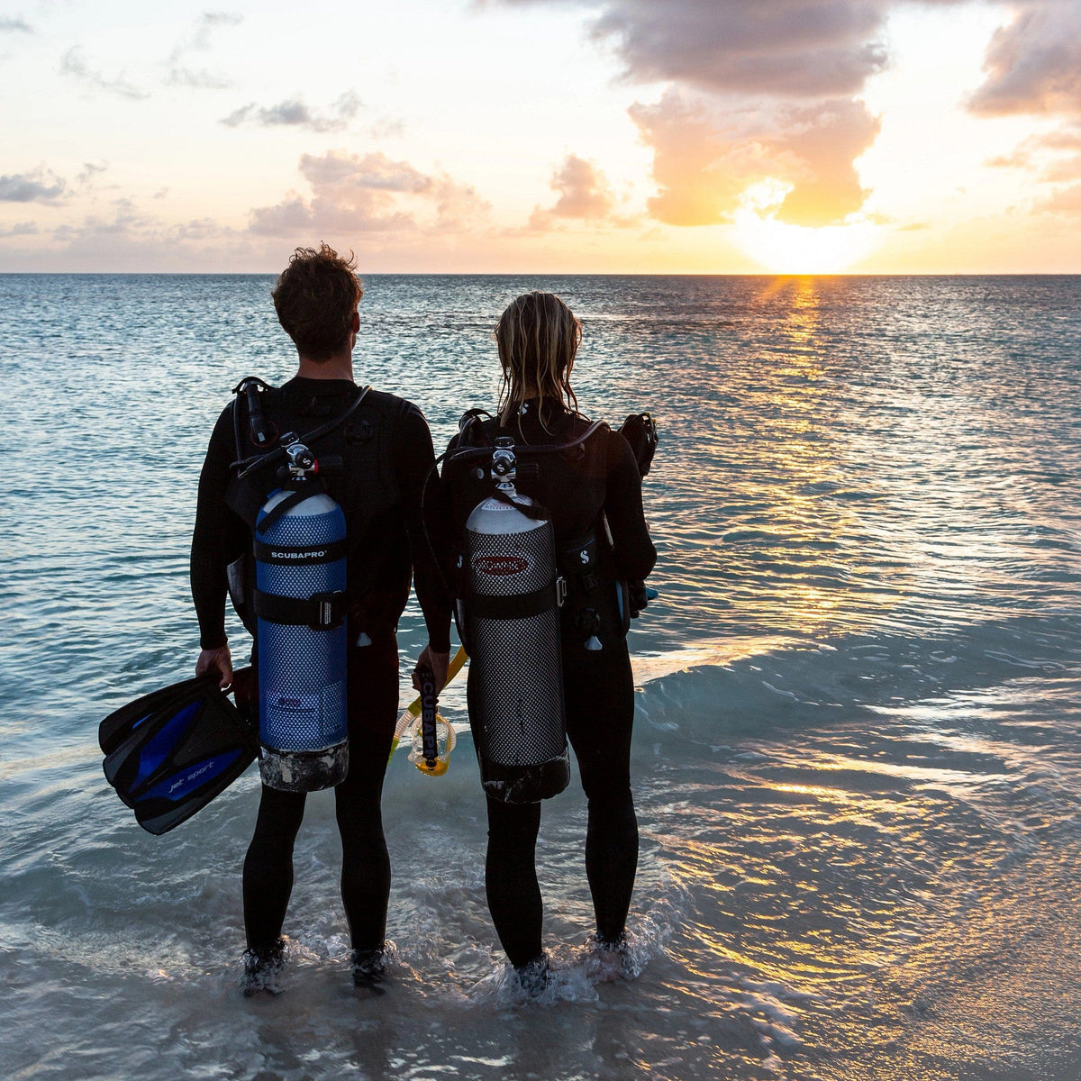 Scuba divers in 5mm steamer wetsuits at sunset