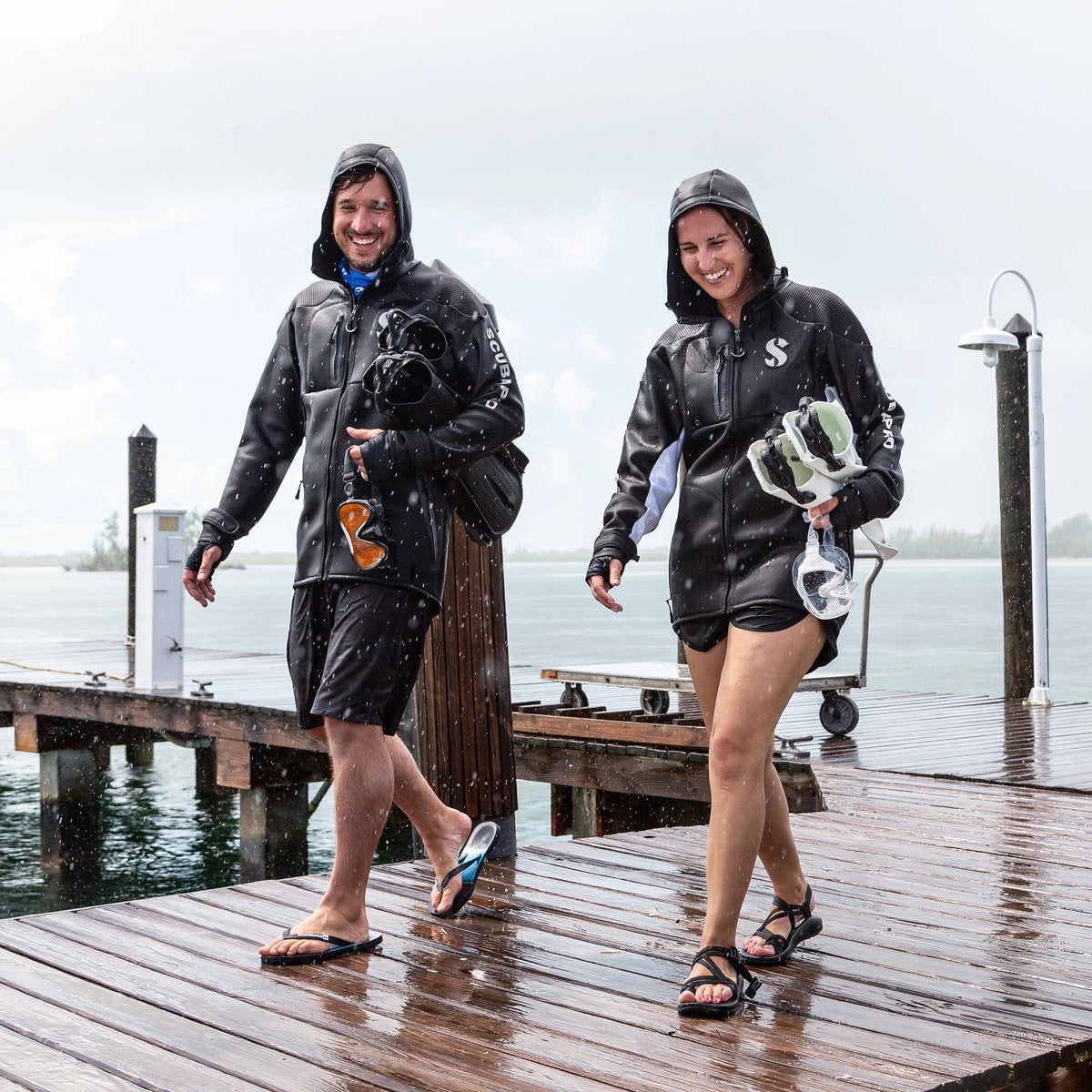 Couple wearing boat coats walking on dock in rain